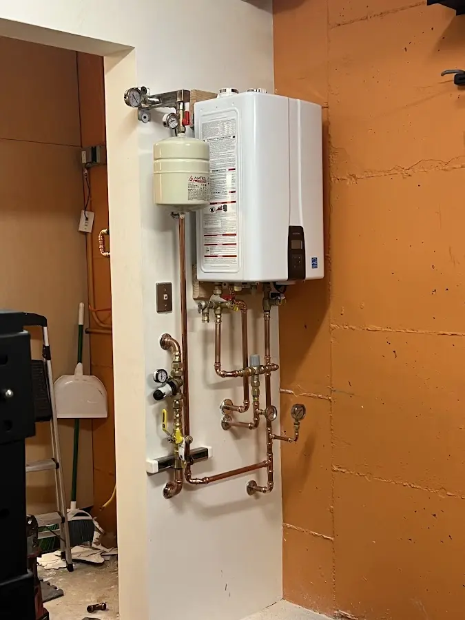 Plumbing technician inspecting water heater connections in Belmont